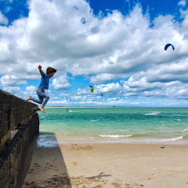 Child jumping from wall onto beach